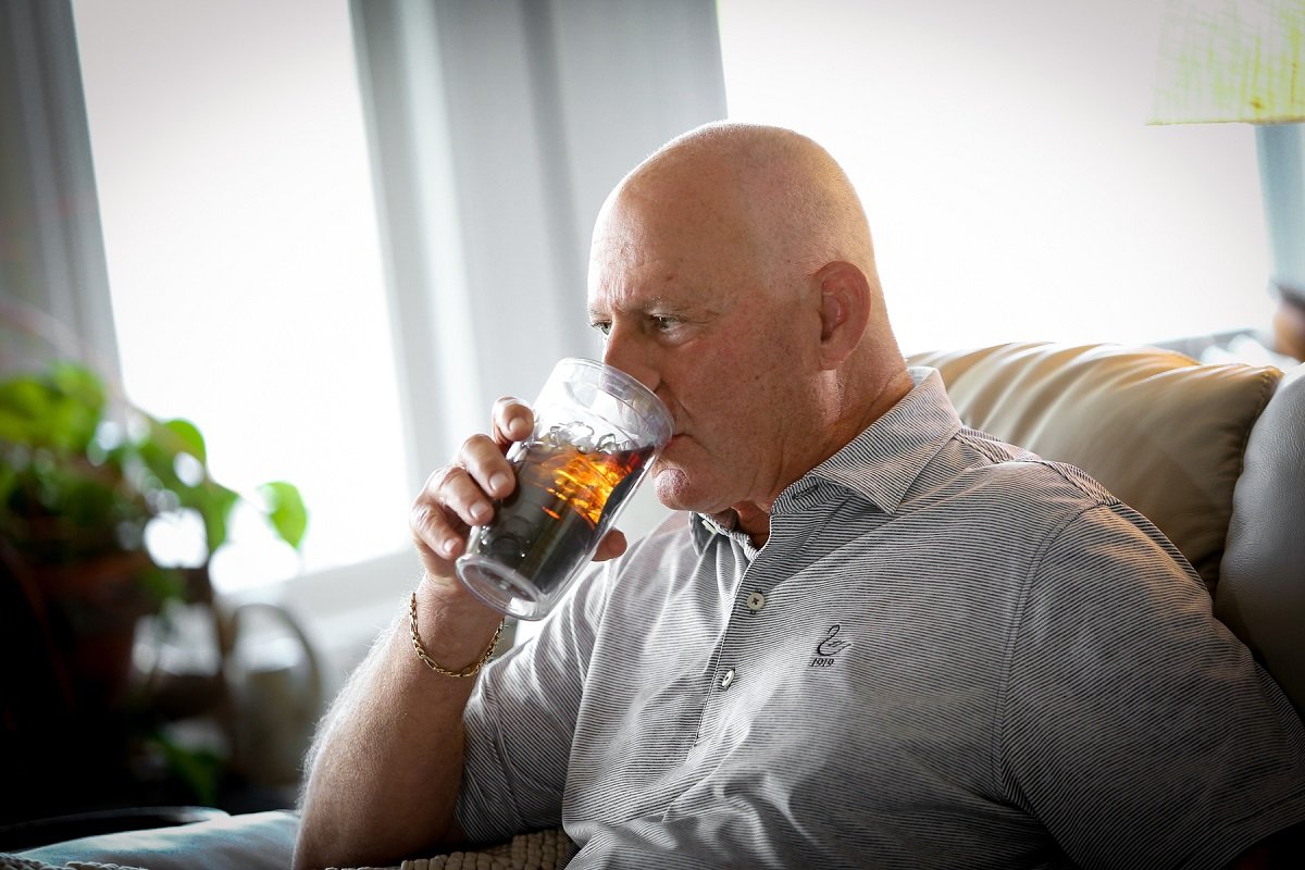 Tom Cioffi showing how he can now pick up a glass and drink from it without tremors.